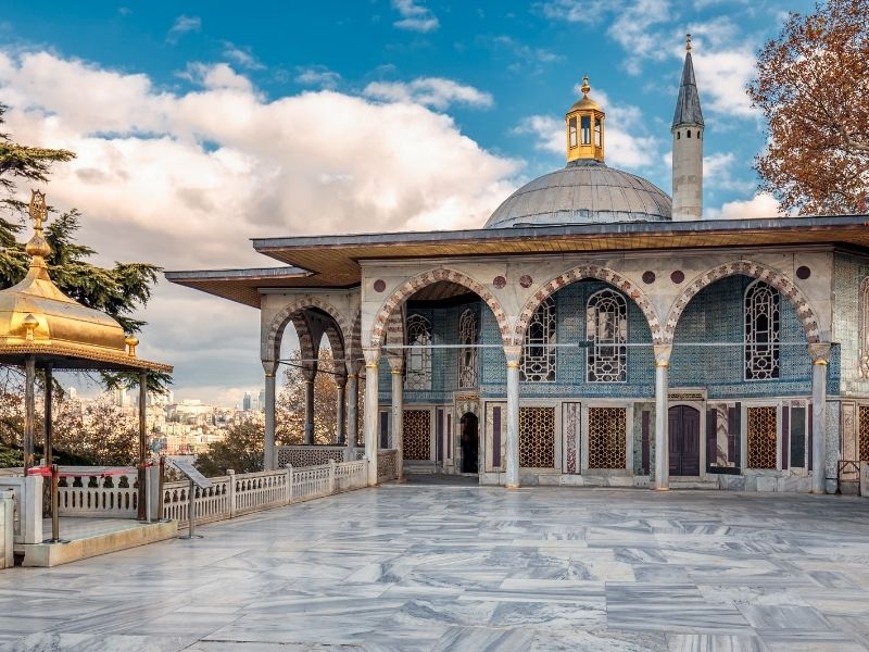 Historical building with ornate arches and blue tiles under a clear sky.