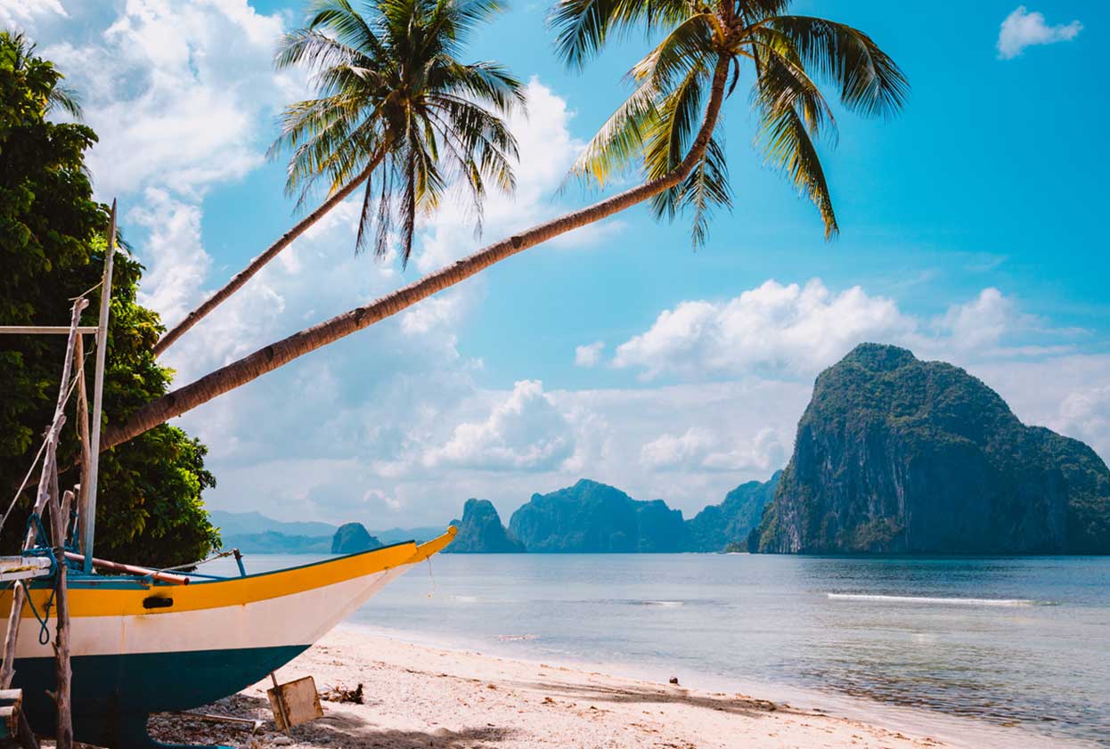 Banca boat on shore under palm trees.Tropical island scenic landscape. El-Nido, Palawan