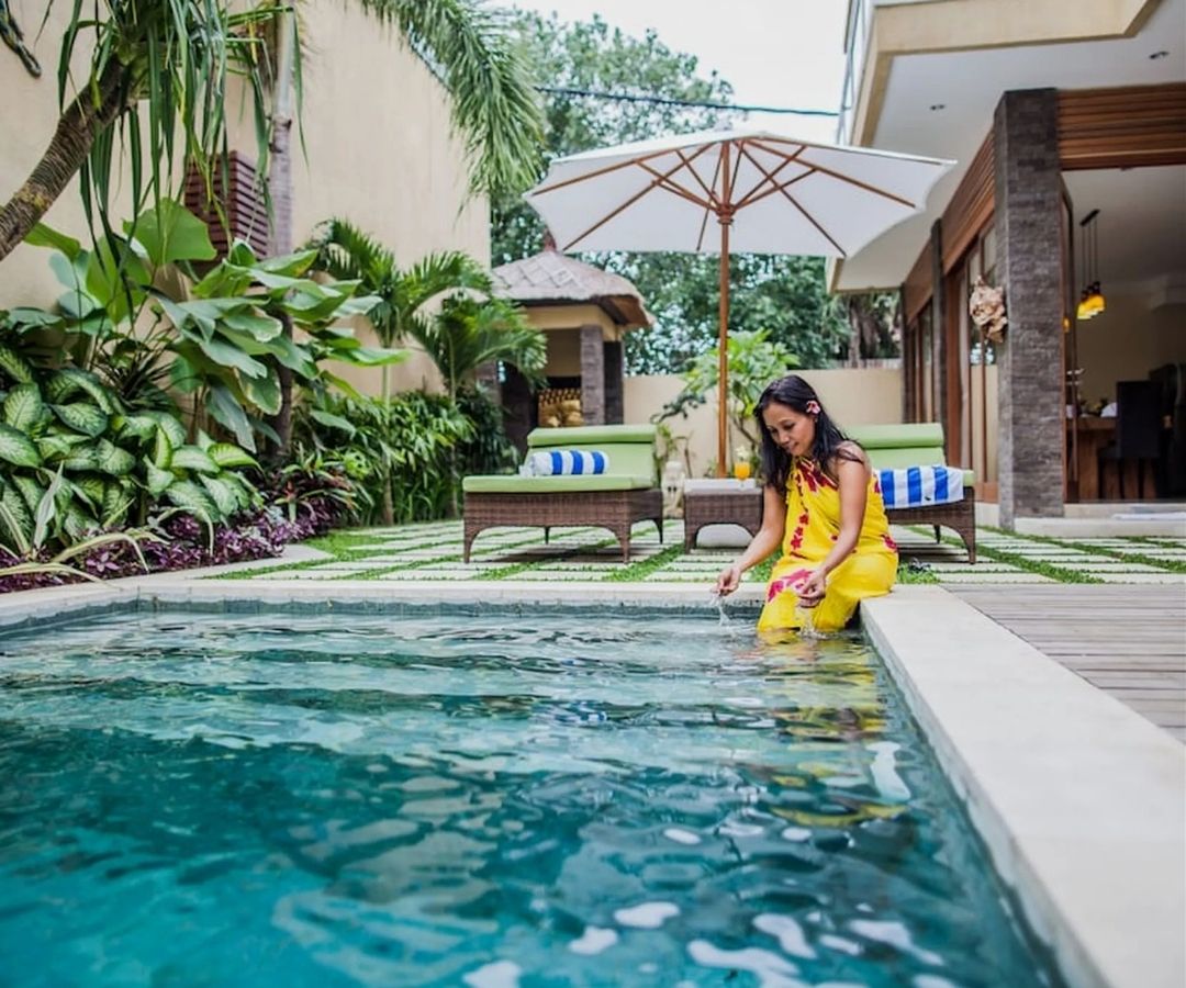Luxurious villa with private pool and happy woman with feet dangling in pool