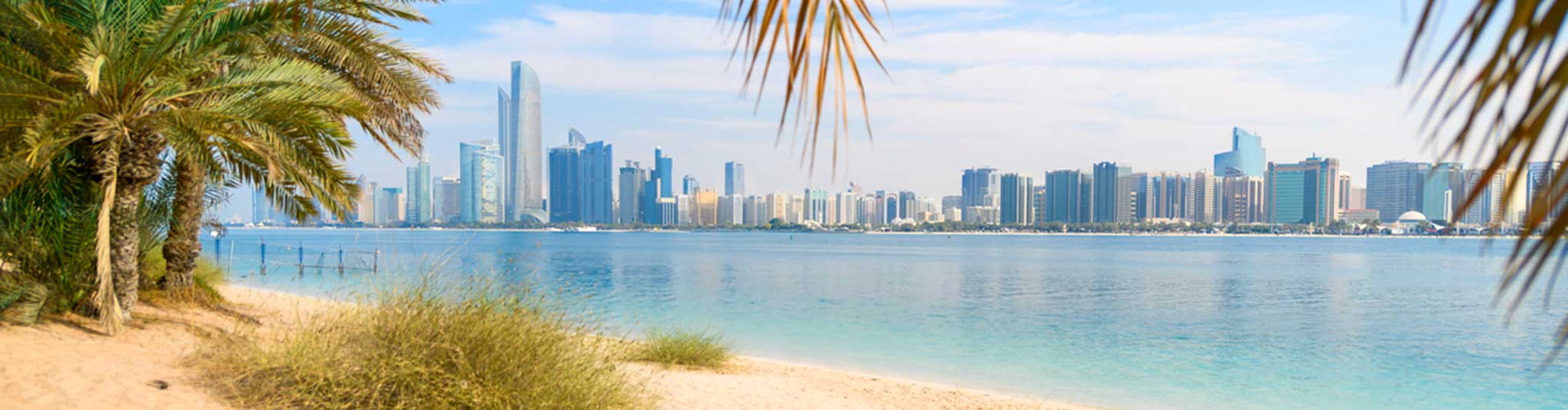 A sandy beach on Marina Mall island with the modern skyline of Abu Dhabi across the water