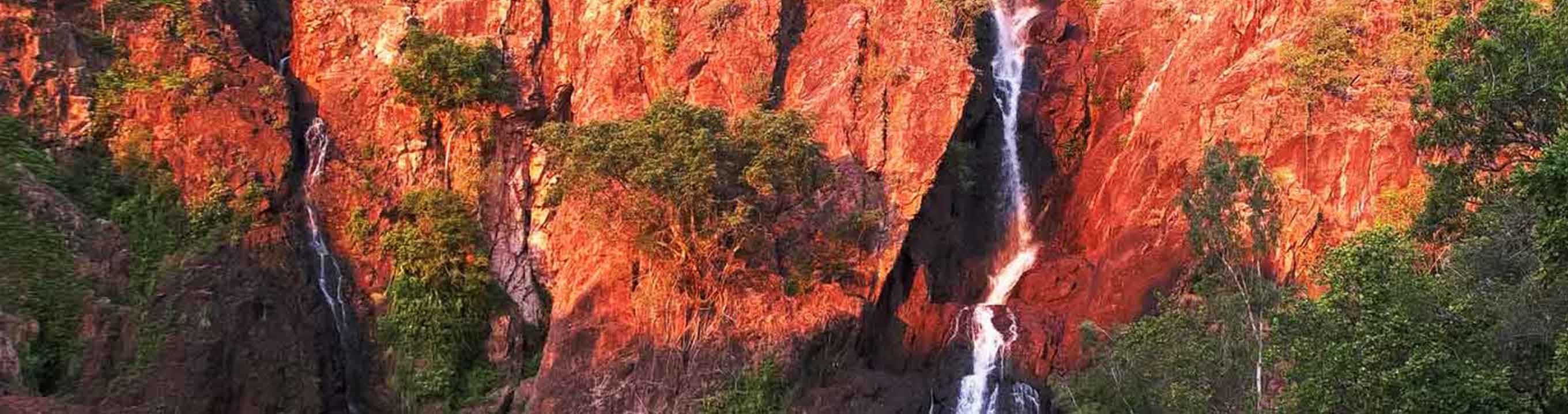 Setting sun turns the cliffs at wangi waterfalls in litchfield national park a brilliant red