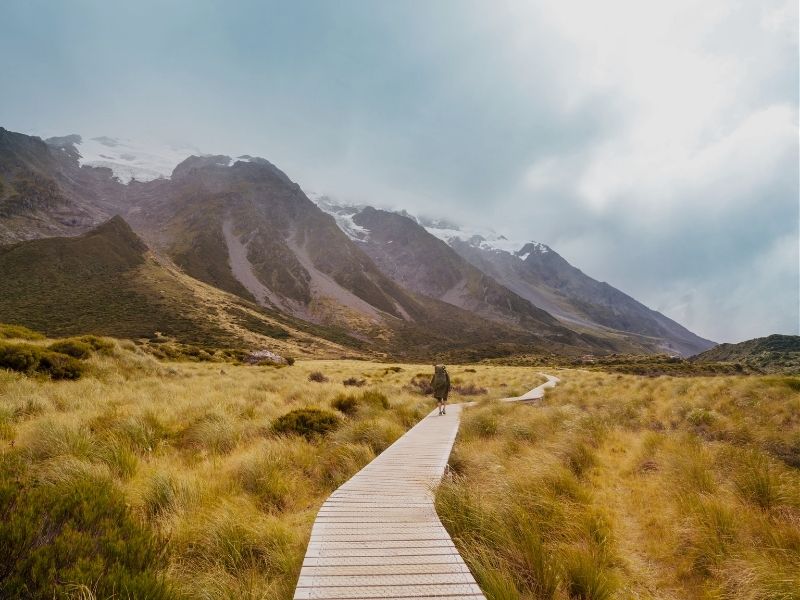 hiker surrounded by snowcapped mountains