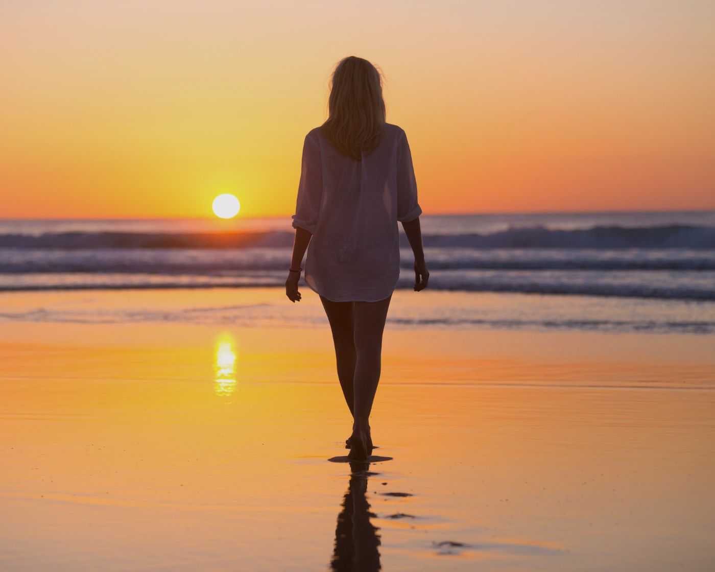 lady walking on beach at sunset