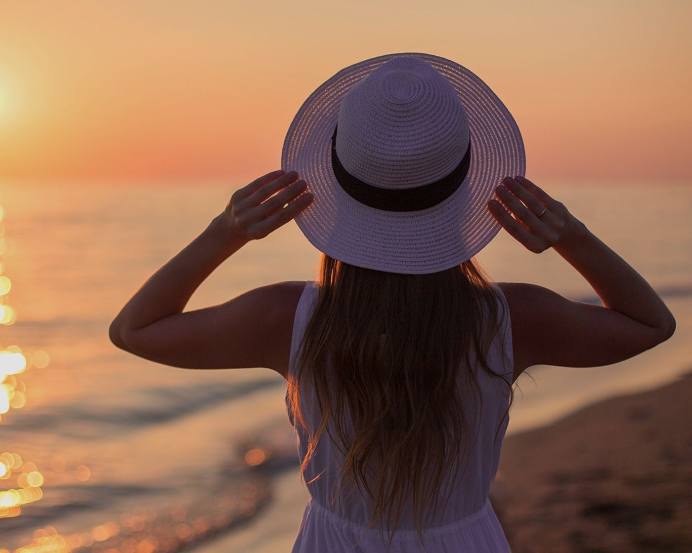lady in hat at beach watching sunst