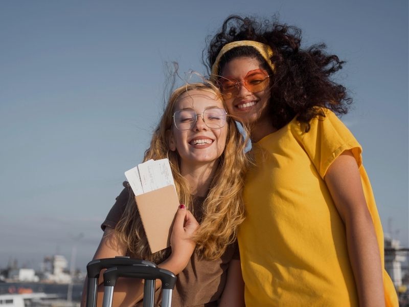 friends smiling with flight boarding passes in hand