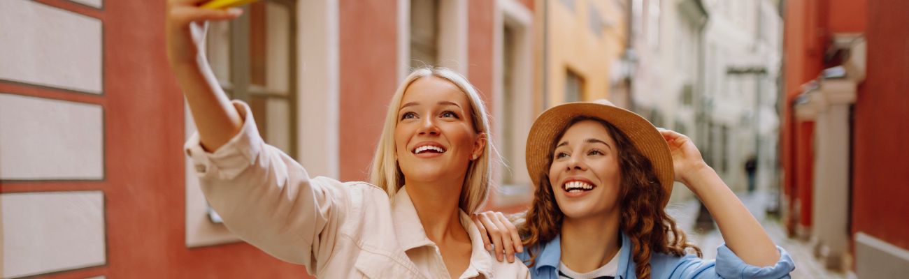 happy female tourists walking along streets in europe take selfies