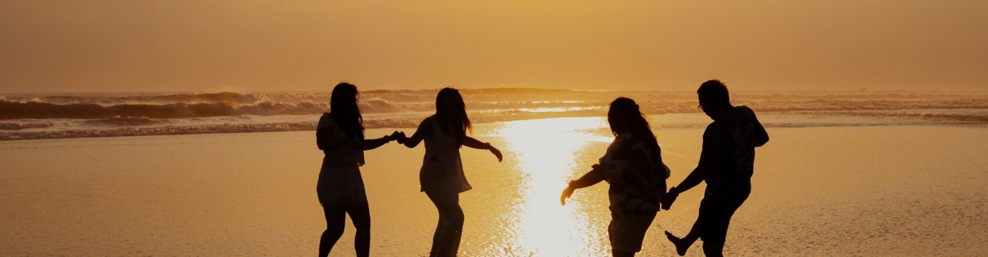 four friends on beach at sunset