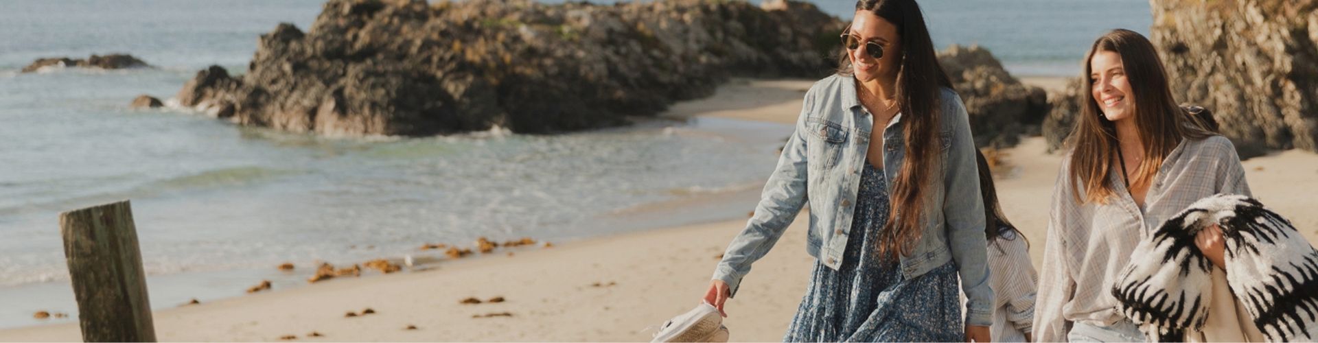 smiling friends walking on beach